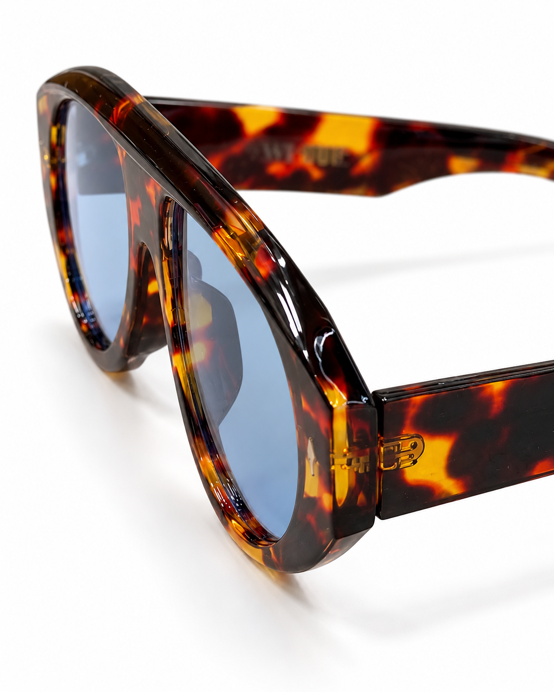 Side angle of oversized tortoiseshell sunglasses with wide temples and blue lenses
