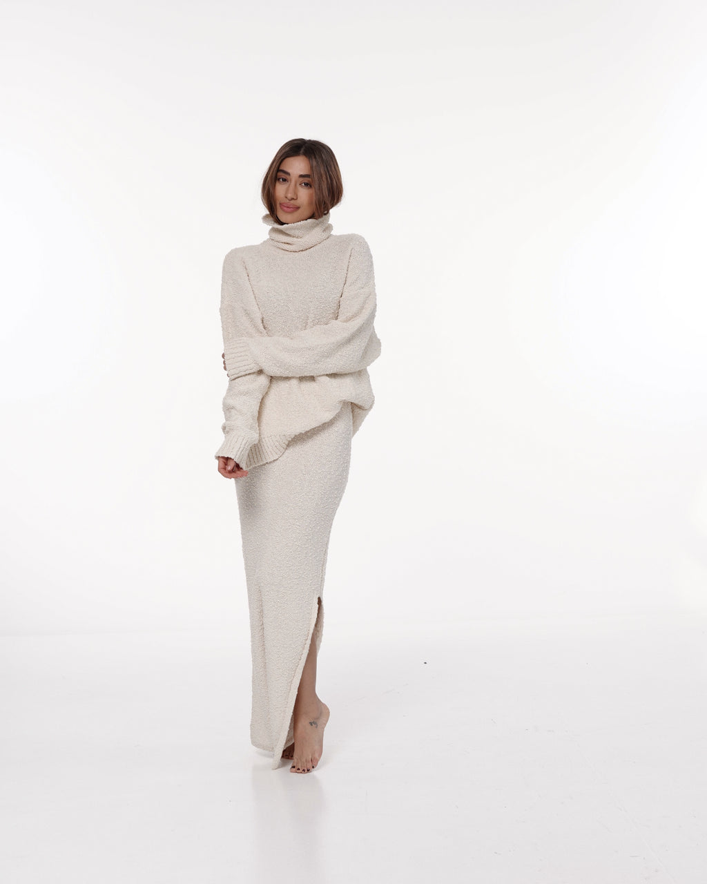 Woman wearing a cream knit maxi skirt and oversized sweater in a studio
