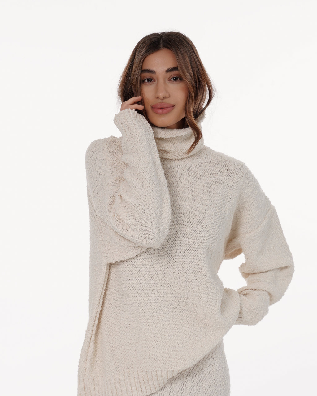 Woman wearing an oversized cream textured knit turtleneck sweater with long sleeves